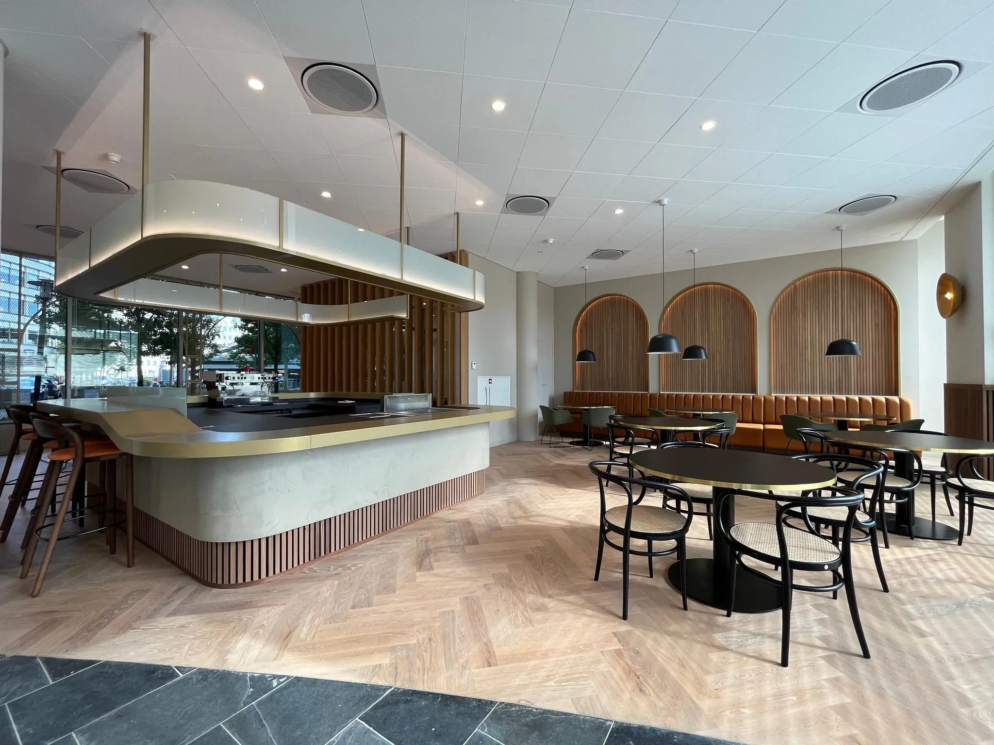Modern interieur van een restaurant aan de Europalaan met een centraal kookeiland, houten vloer en stijlvolle zitplekken.