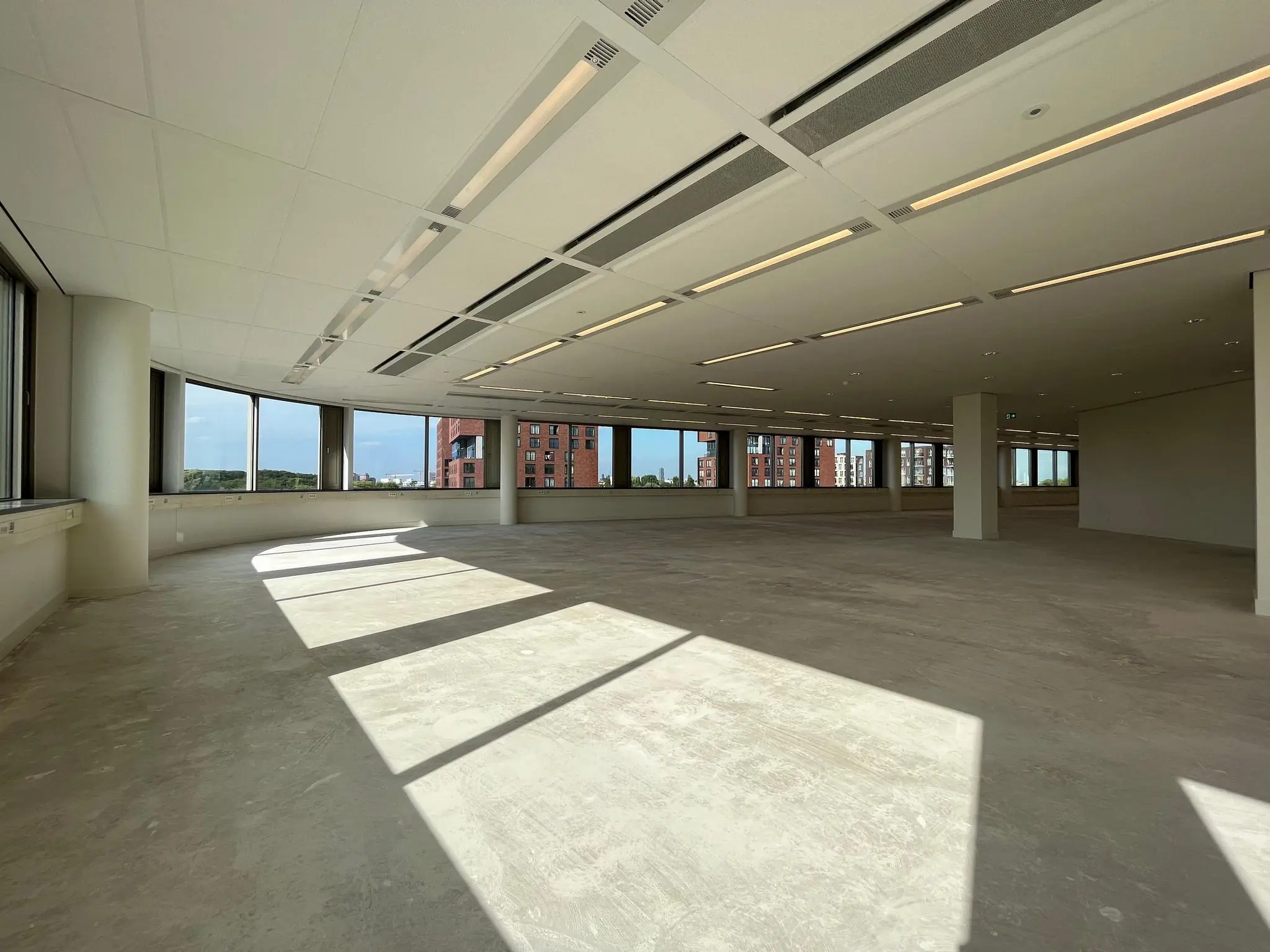 Lichte, lege kantoorruimte aan de Europalaan met grote ramen en uitzicht op omliggende gebouwen.