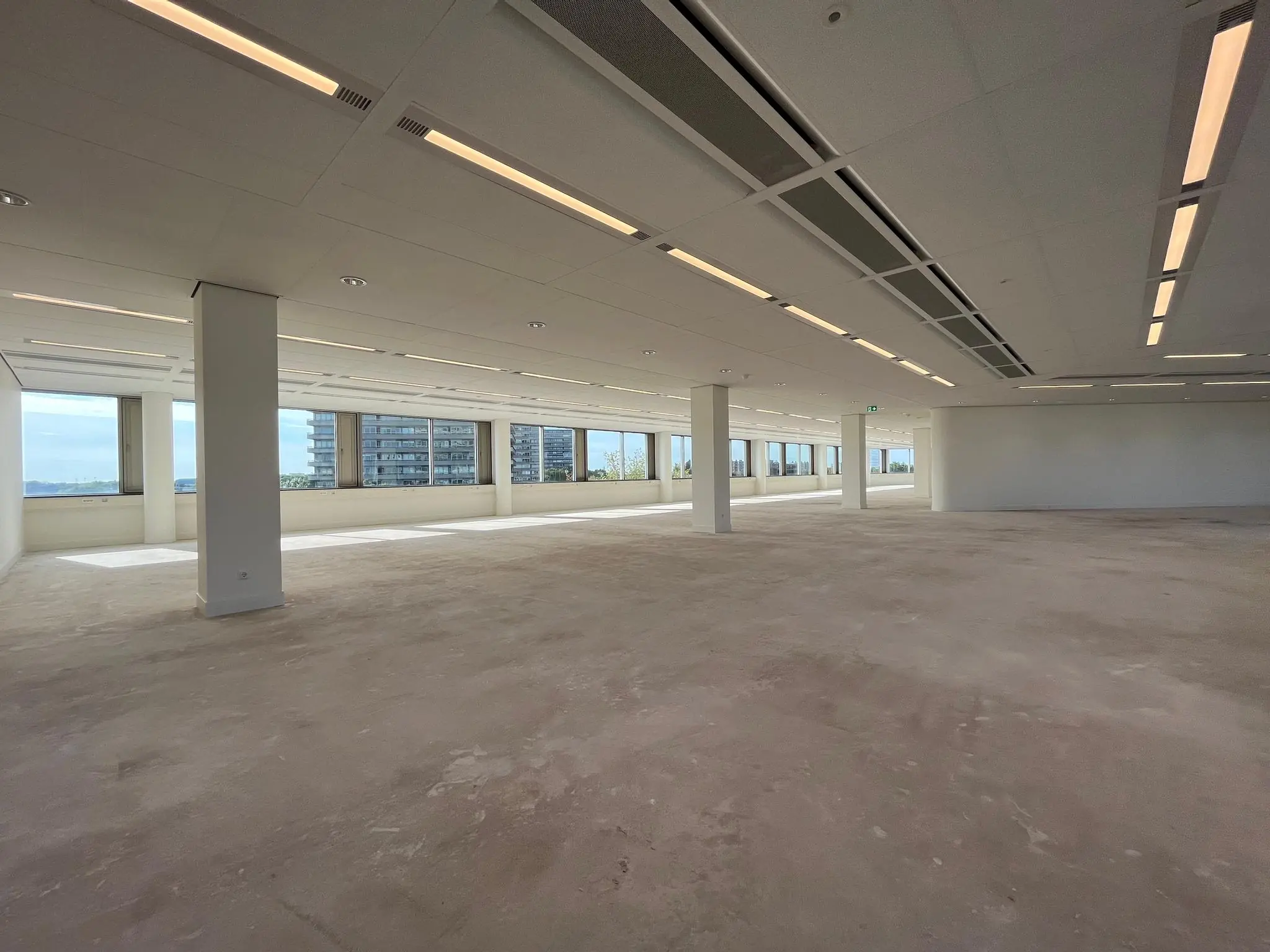Leeg kantoorpand aan de Europalaan met grote ramen en betonnen vloer.