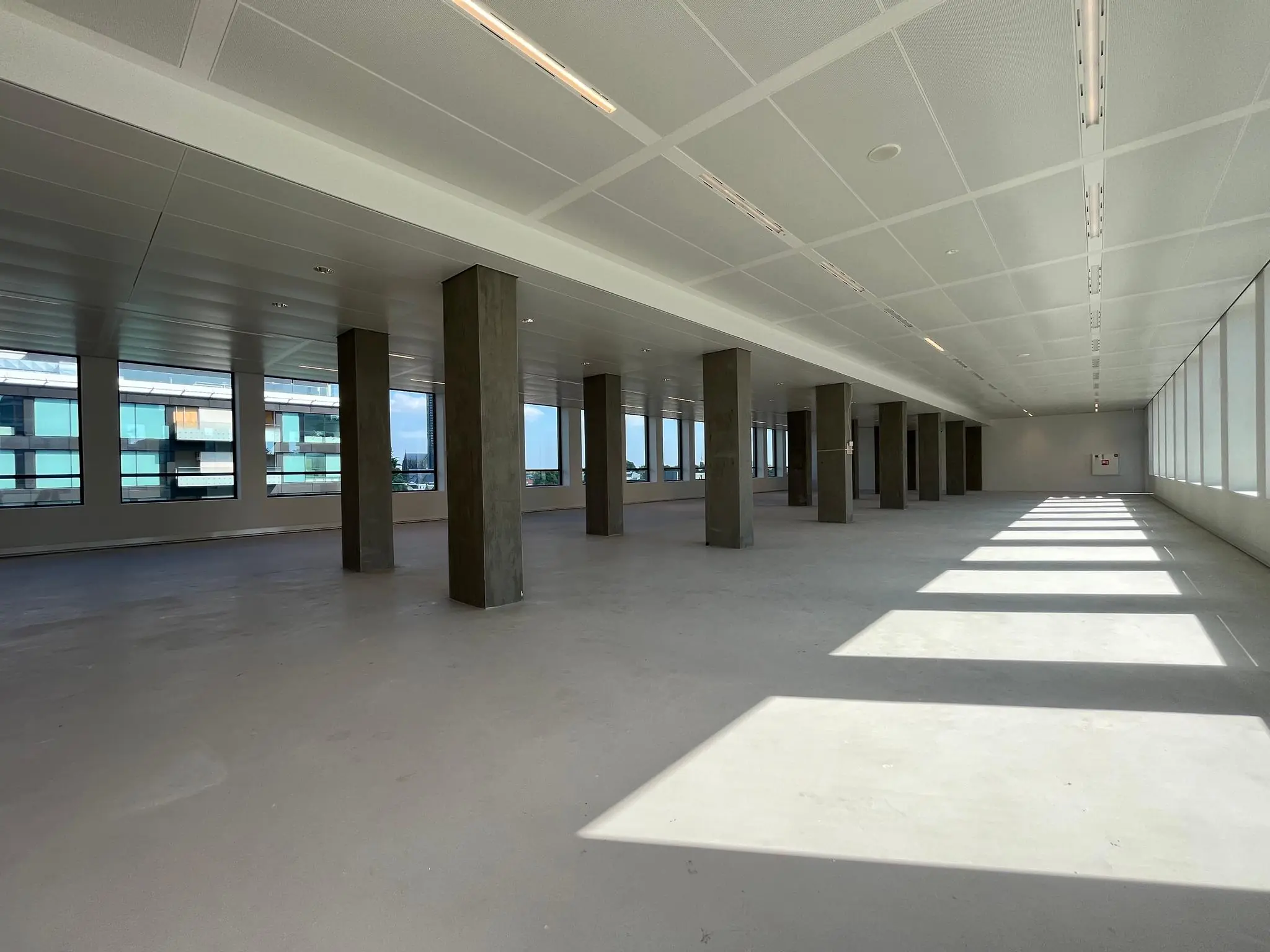 Lichte, lege kantoorruimte aan de Catharijnesingel met betonnen pilaren en grote ramen.