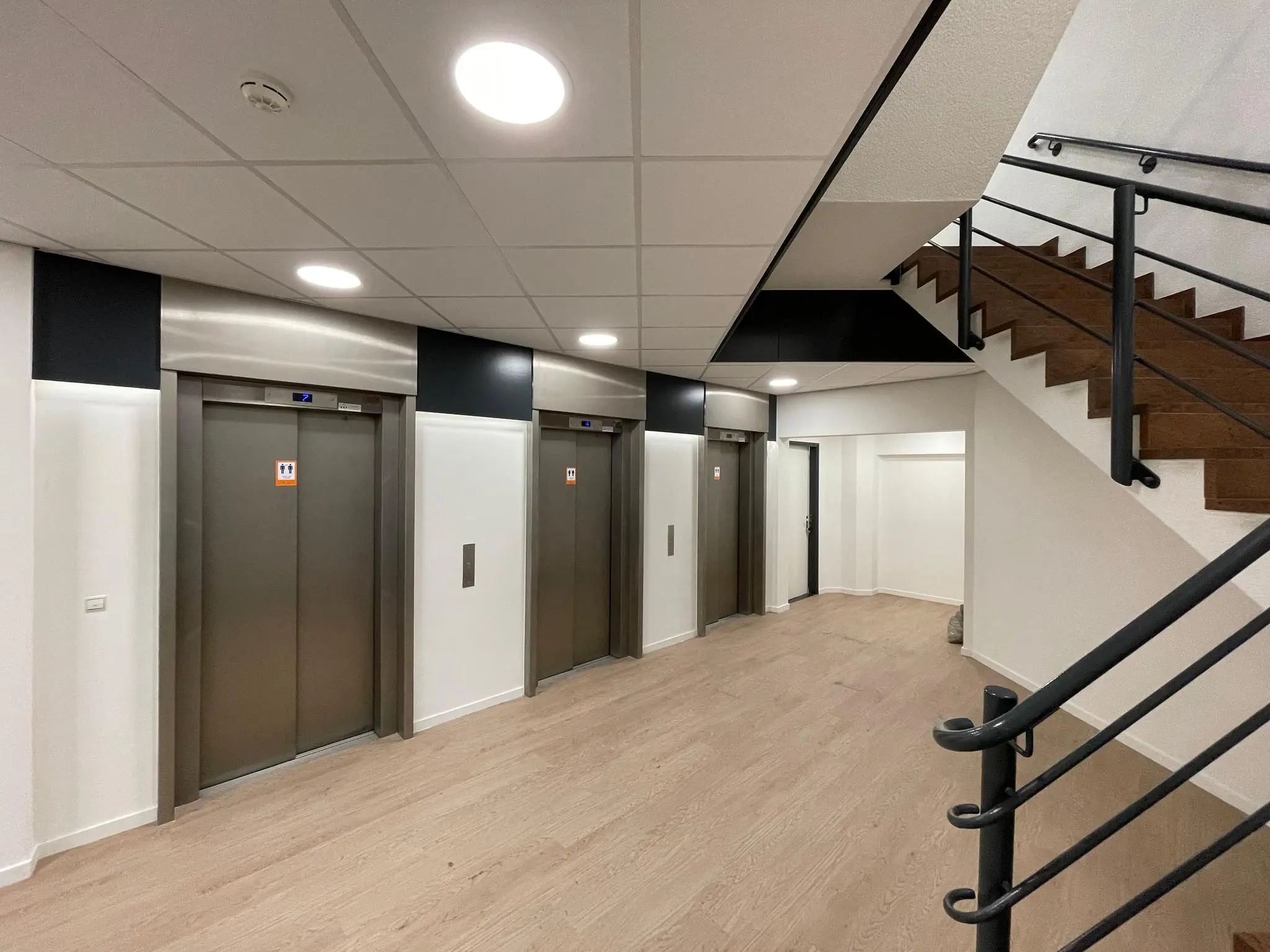 Moderne hal met drie liften en een houten trap aan de Overschieseweg.