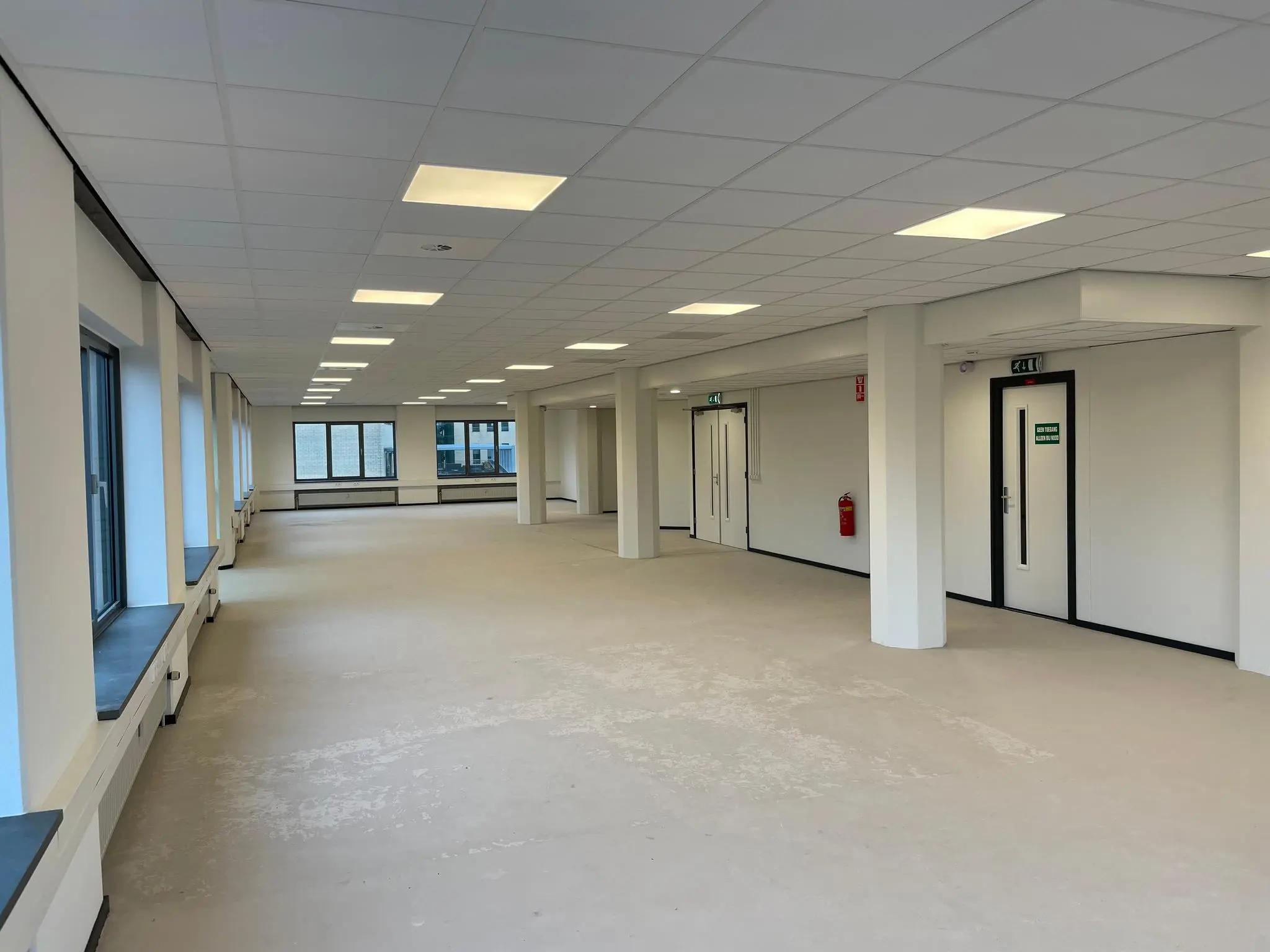 Lichte en moderne lege kantoorruimte aan de Overschieseweg met systeemplafond en grote ramen.