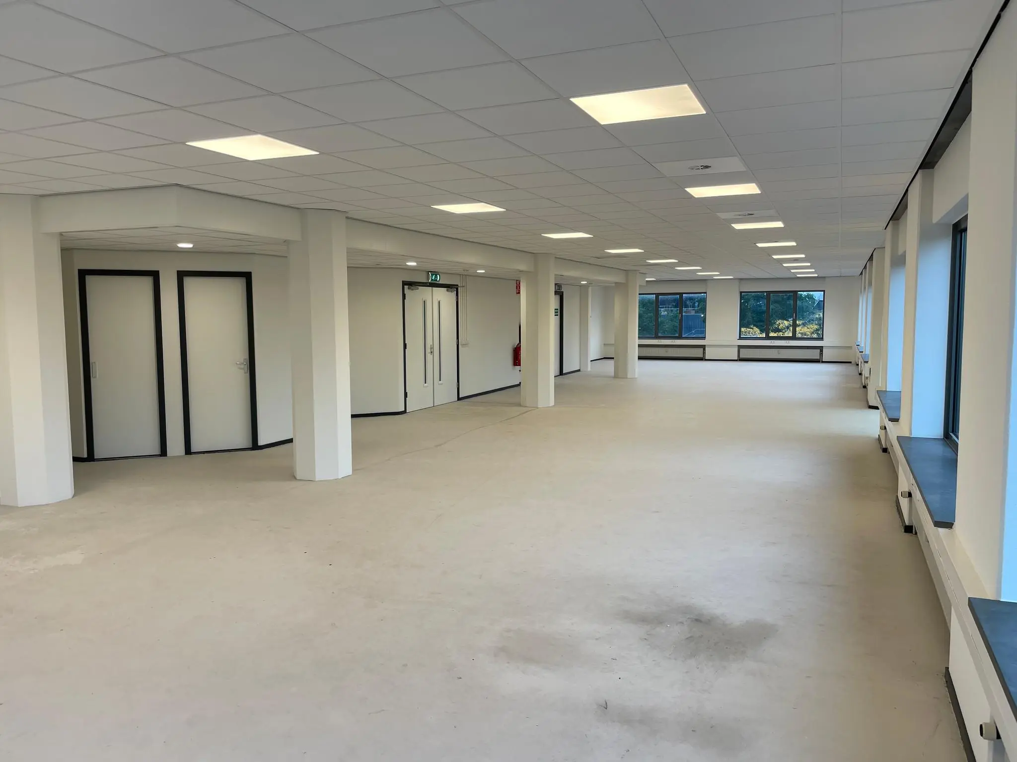 Licht en ruim kantoorpand aan de Overschieseweg met witte wanden, systeemplafond en grote ramen.