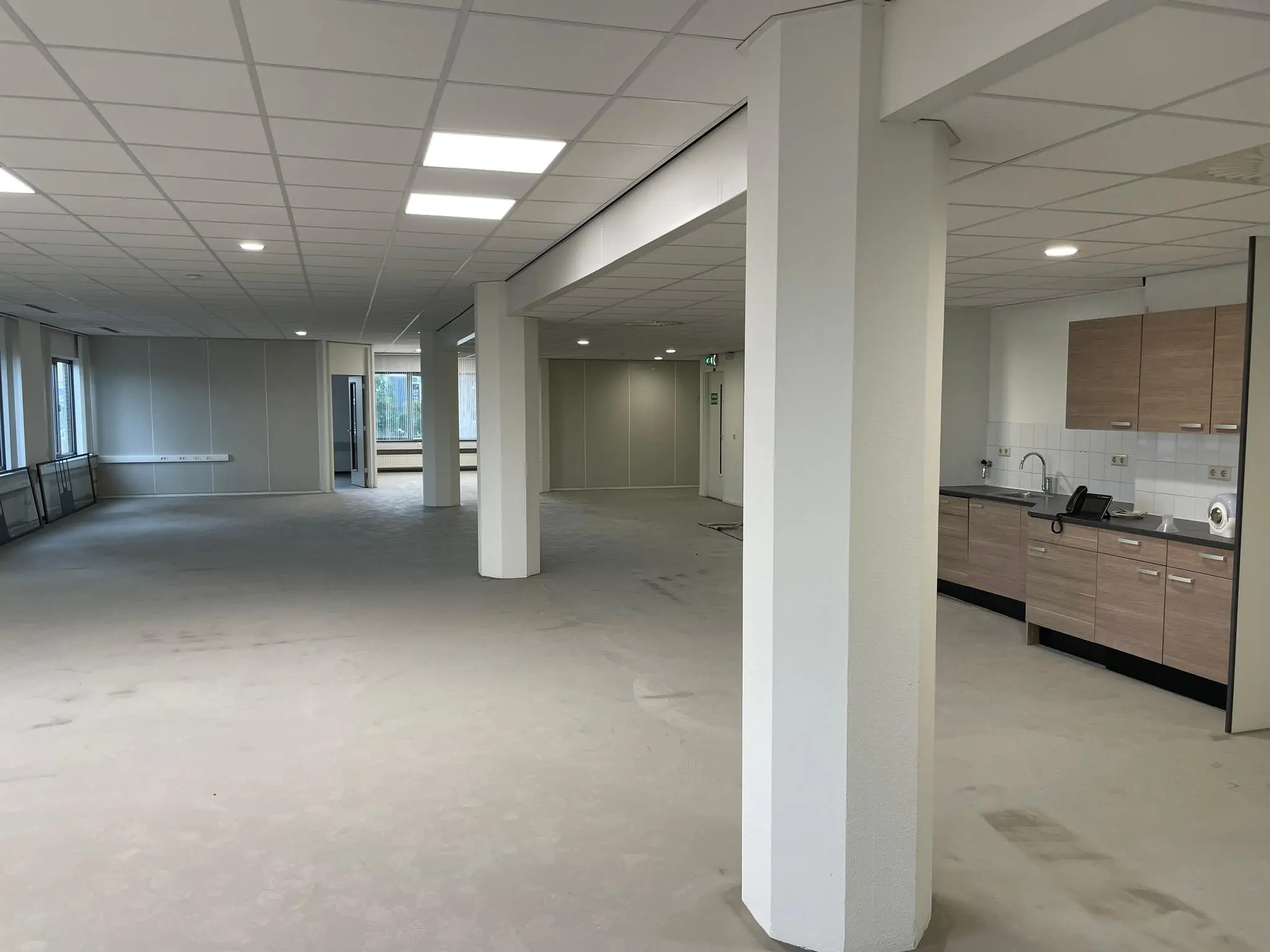 Leeg kantoorpand aan de Overschieseweg met open ruimte, systeemplafond en pantry.