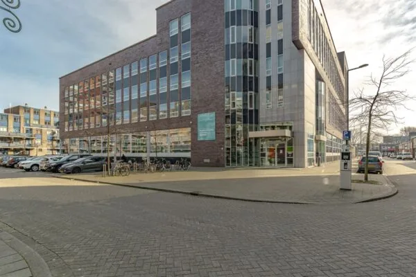 Modern kantoorgebouw aan de Dynamostraat met geparkeerde auto’s en fietsen op de voorgrond.