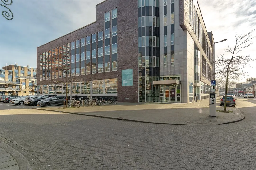 Modern kantoorgebouw aan de Dynamostraat met geparkeerde auto’s en fietsen op de voorgrond.