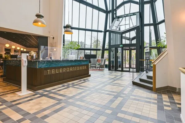 Moderne ontvangsthal van het Teleport Tower-gebouw met hoge glazen ramen en een receptiebalie.