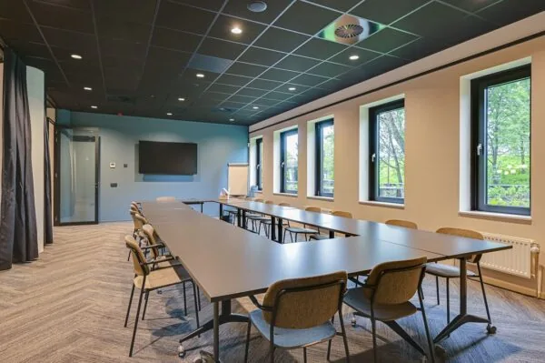 Vergaderruimte aan de Kingsfordweg met U-vormige opstelling, moderne inrichting en grote ramen met uitzicht op groen.