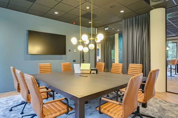 Moderne vergaderruimte aan de Kingsfordweg met leren stoelen, groot scherm en sfeerverlichting.