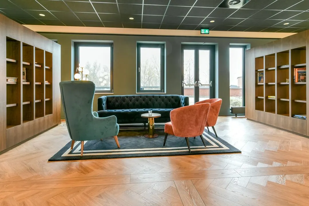Moderne en sfeervol ingerichte wachtruimte met kleurrijke fauteuils, een donkere bank en boekenkasten aan Kingsfordweg.