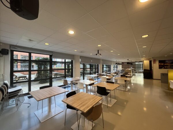 Moderne, ruime kantine met houten tafels en zwarte en witte stoelen aan de Zonnebaan.