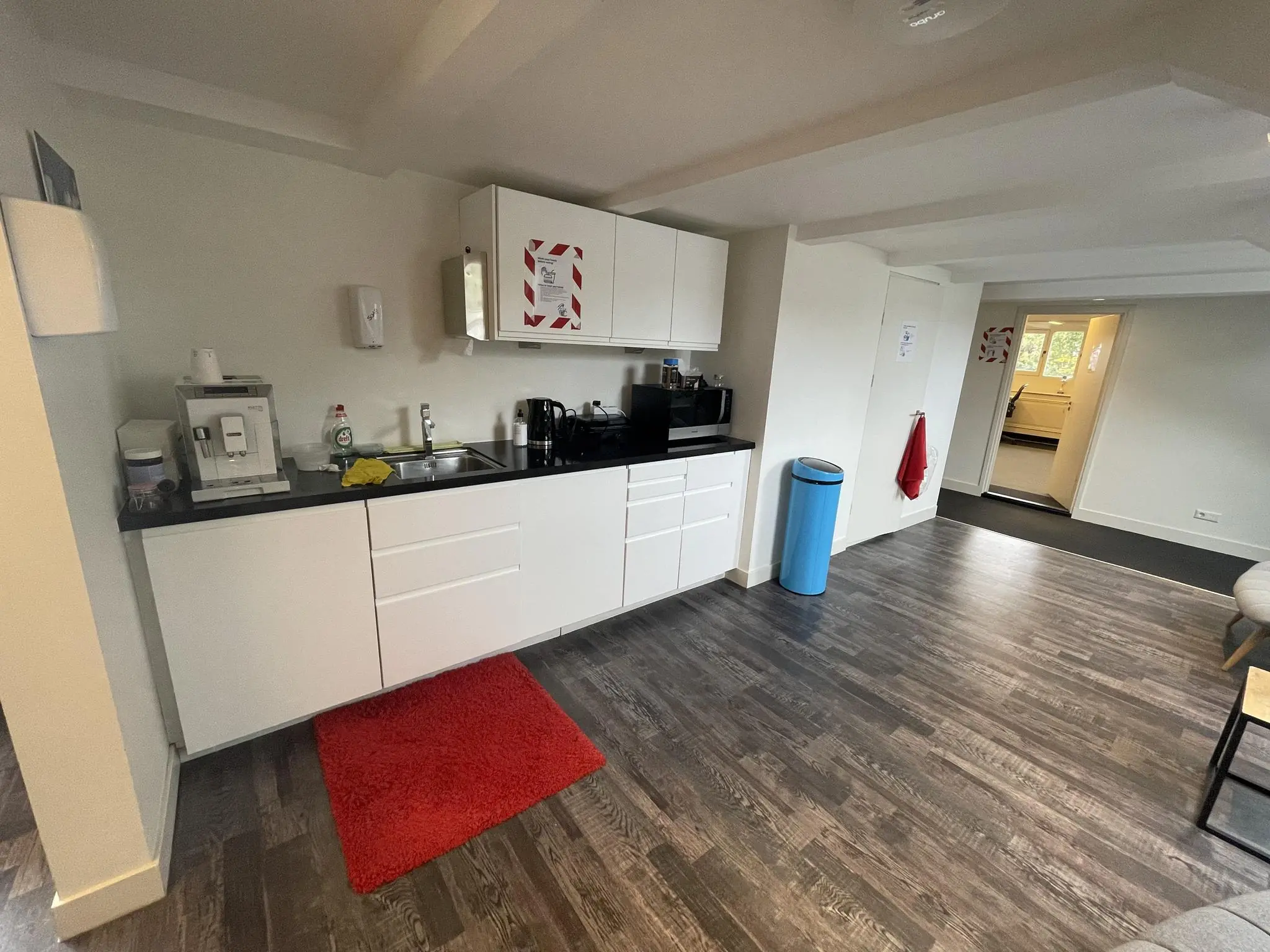 Keukenruimte aan de Herengracht met witte kasten, koffiezetapparaat, magnetron en blauwe afvalbak.