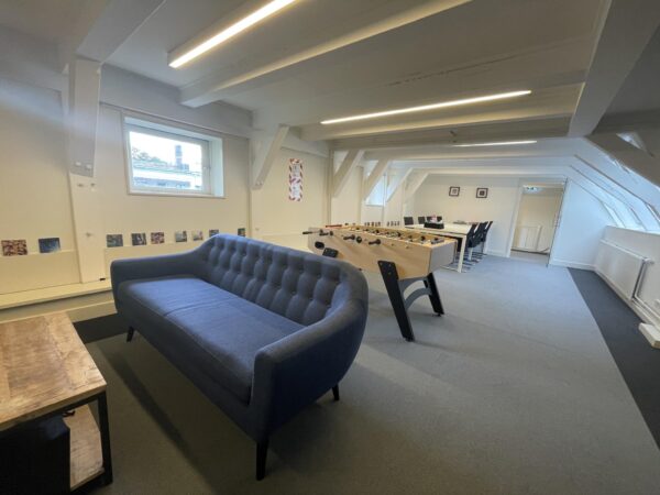 Modern ingerichte kantoorruimte aan de Herengracht met een blauwe bank, tafelvoetbaltafel en vergadertafel.