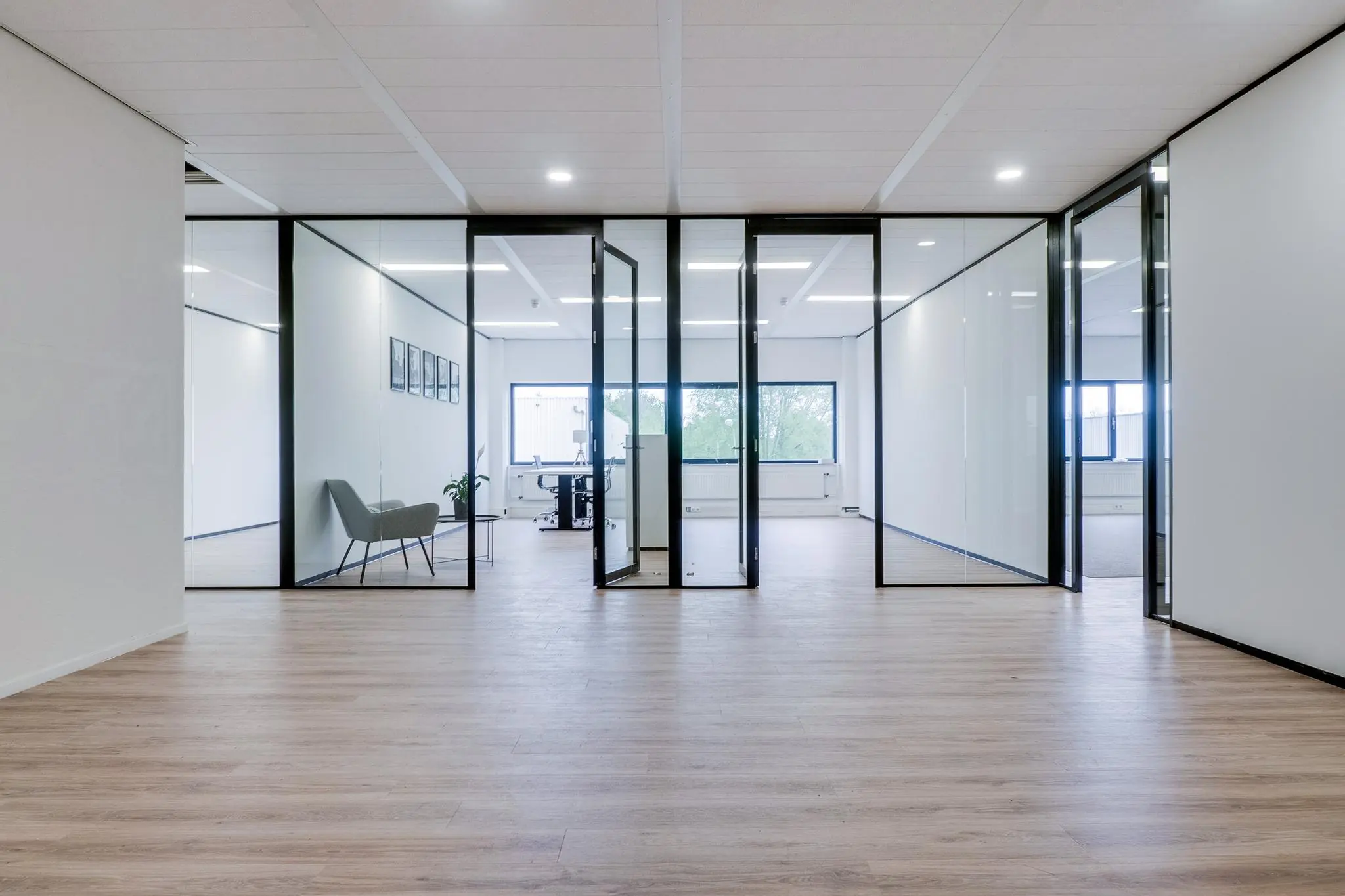 Moderne kantoorruimte aan de Zonnebaan met glazen wanden, houten vloer en minimalistische inrichting.