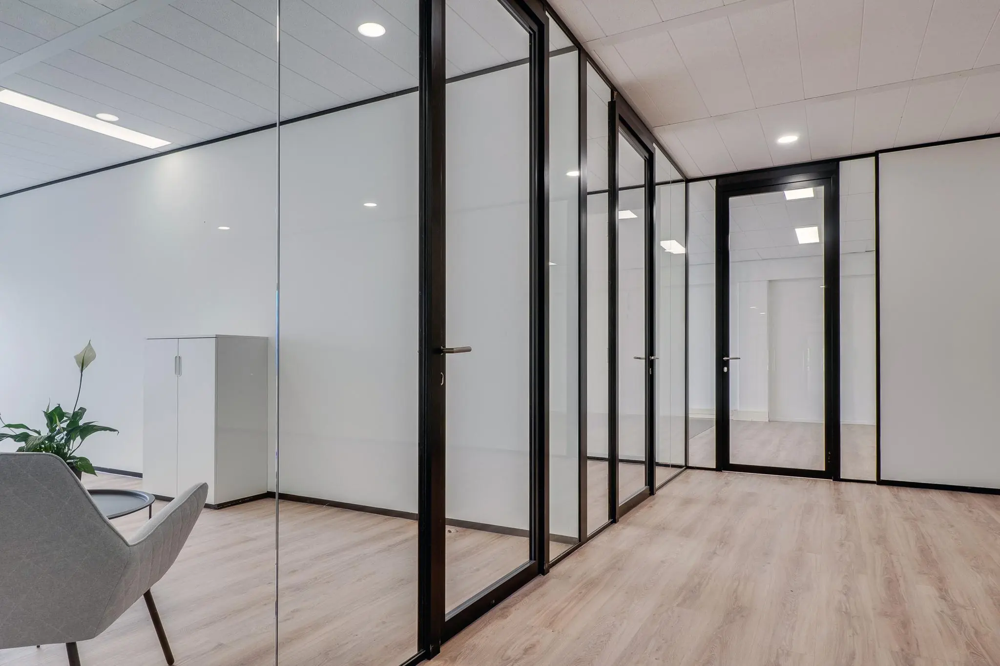 Moderne kantoorruimte aan de Zonnebaan met glazen wanden, houten vloer en strakke afwerking.