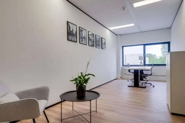 Modern ingericht kantoor aan de Zonnebaan met een bureau, zithoek en grote raampartij.