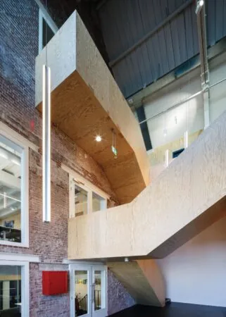 Houten trap met moderne verlichting in een gerenoveerd bakstenen interieur aan de Nassaukade.