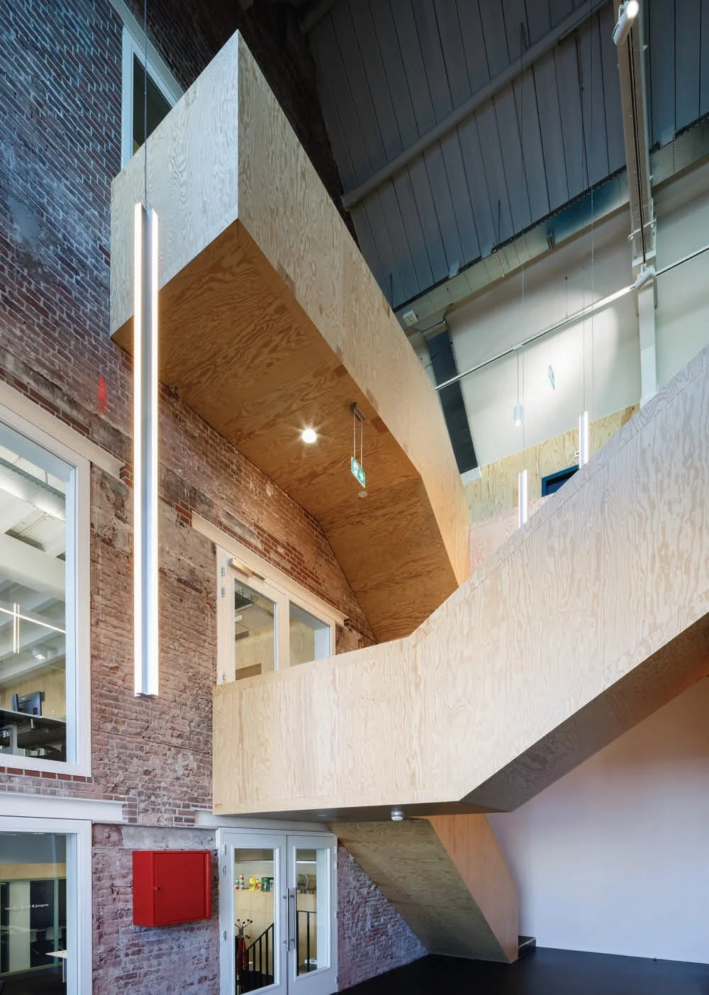 Houten trap met moderne verlichting in een gerenoveerd bakstenen interieur aan de Nassaukade.