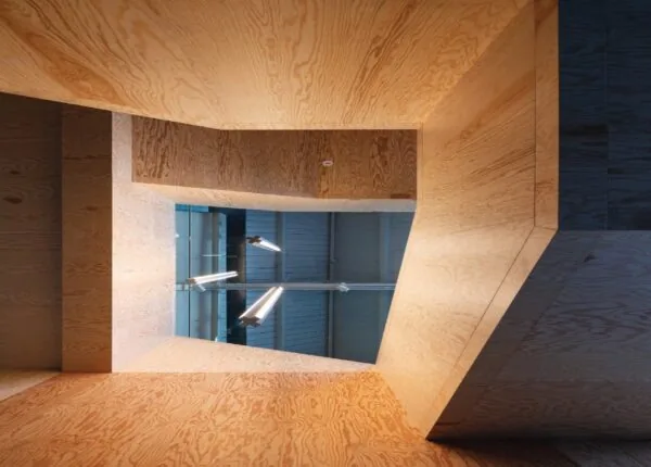 Houten interieur met een geometrisch raampartij aan de Nassaukade en moderne hanglampen erboven.