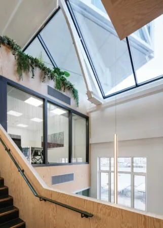 Interieur van een modern kantoorgebouw aan de Nassaukade met houten afwerking, grote ramen en een schuin glazen dak.