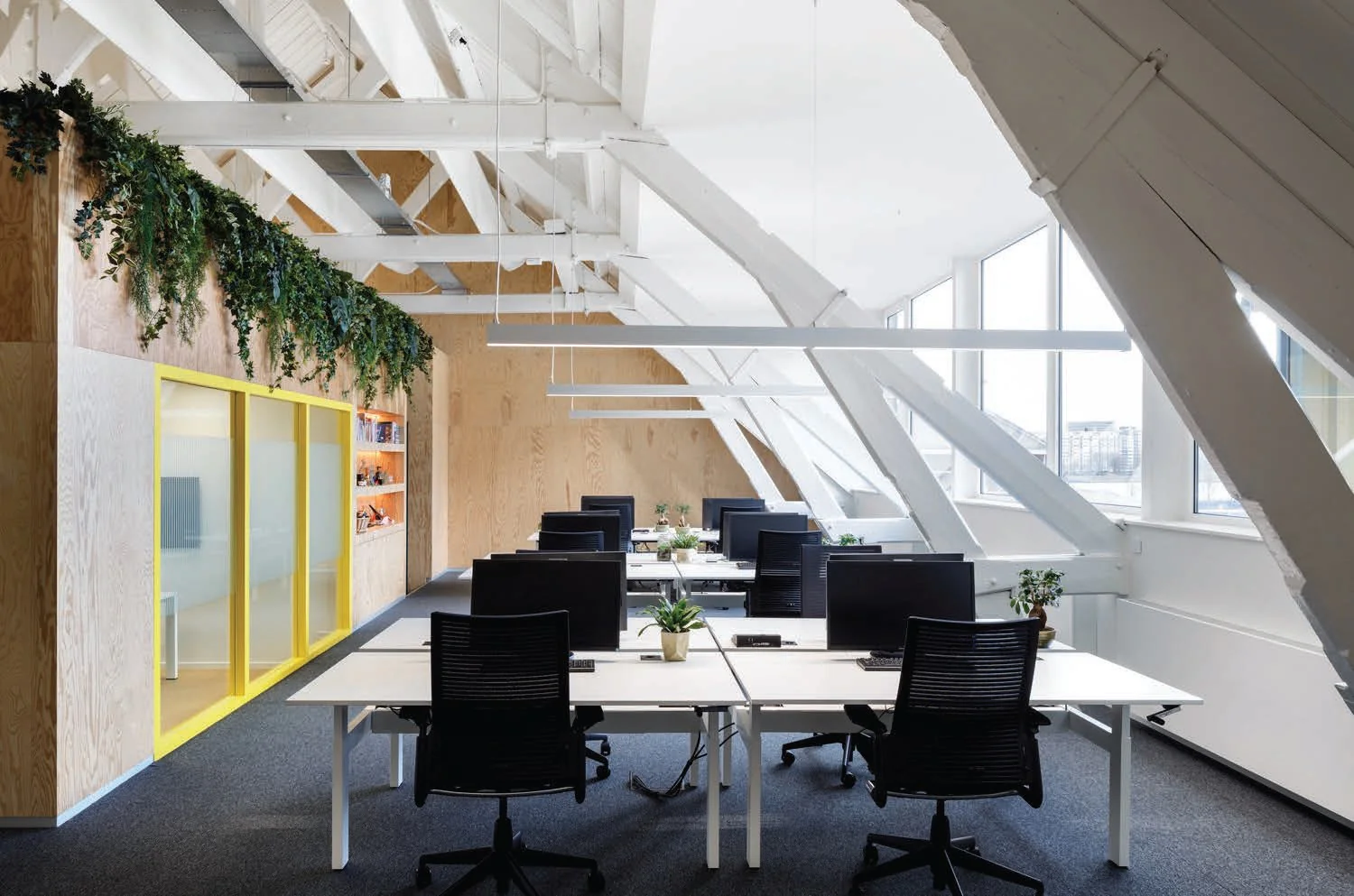 Modern kantoorinterieur aan de Nassaukade met open werkplekken, witte balken en veel natuurlijk licht.