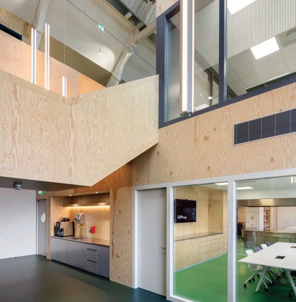 Moderne kantoorruimte aan de Nassaukade met houten wanden, een open keuken en vergaderruimte met glazen wanden.