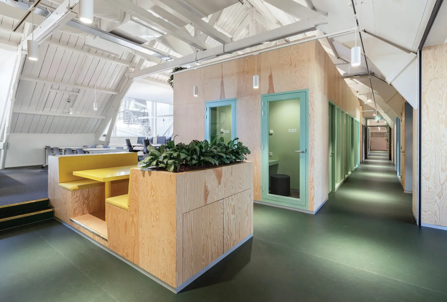 Modern kantoorpand aan de Nassaukade met houten wanden, vergaderruimtes, werkplekken en een ingebouwde zithoek met plantenbak.