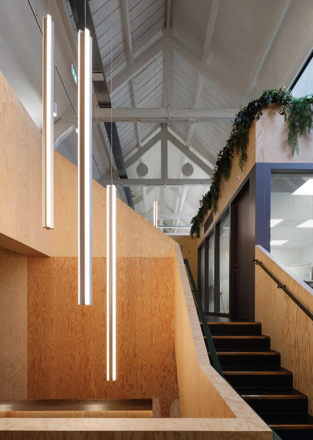 Moderne houten trap met hangende LED-verlichting in een kantoorruimte aan de Nassaukade.