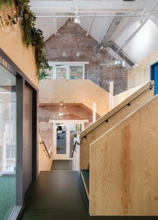 Moderne kantoorruimte aan de Nassaukade met houten wanden, een industriële bakstenen muur en groene accenten.