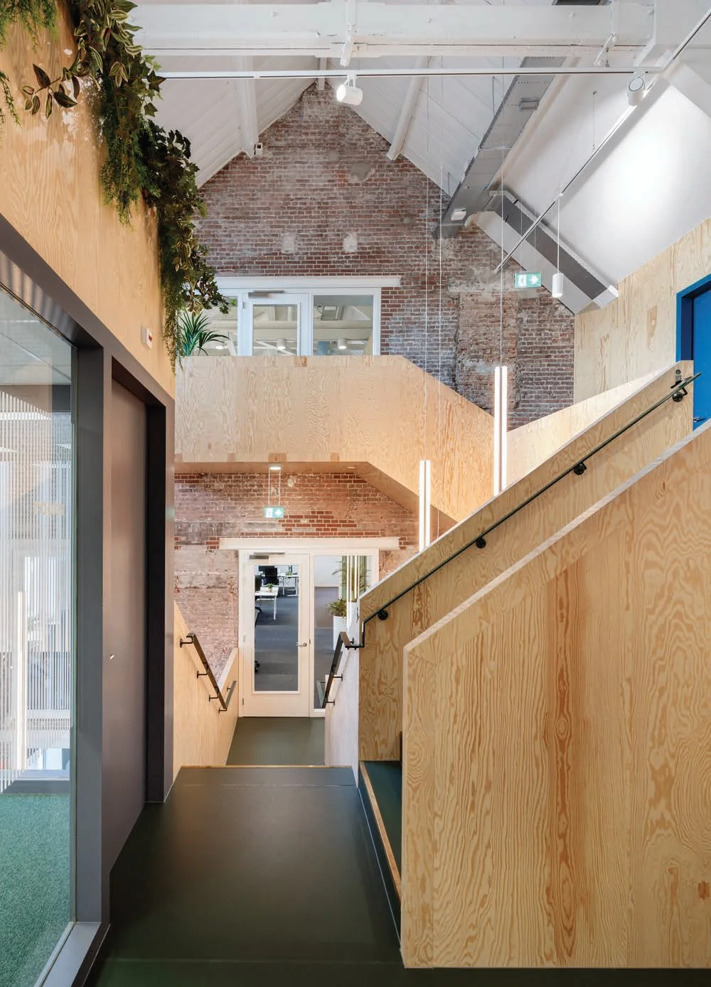 Moderne kantoorruimte aan de Nassaukade met houten wanden, een industriële bakstenen muur en groene accenten.