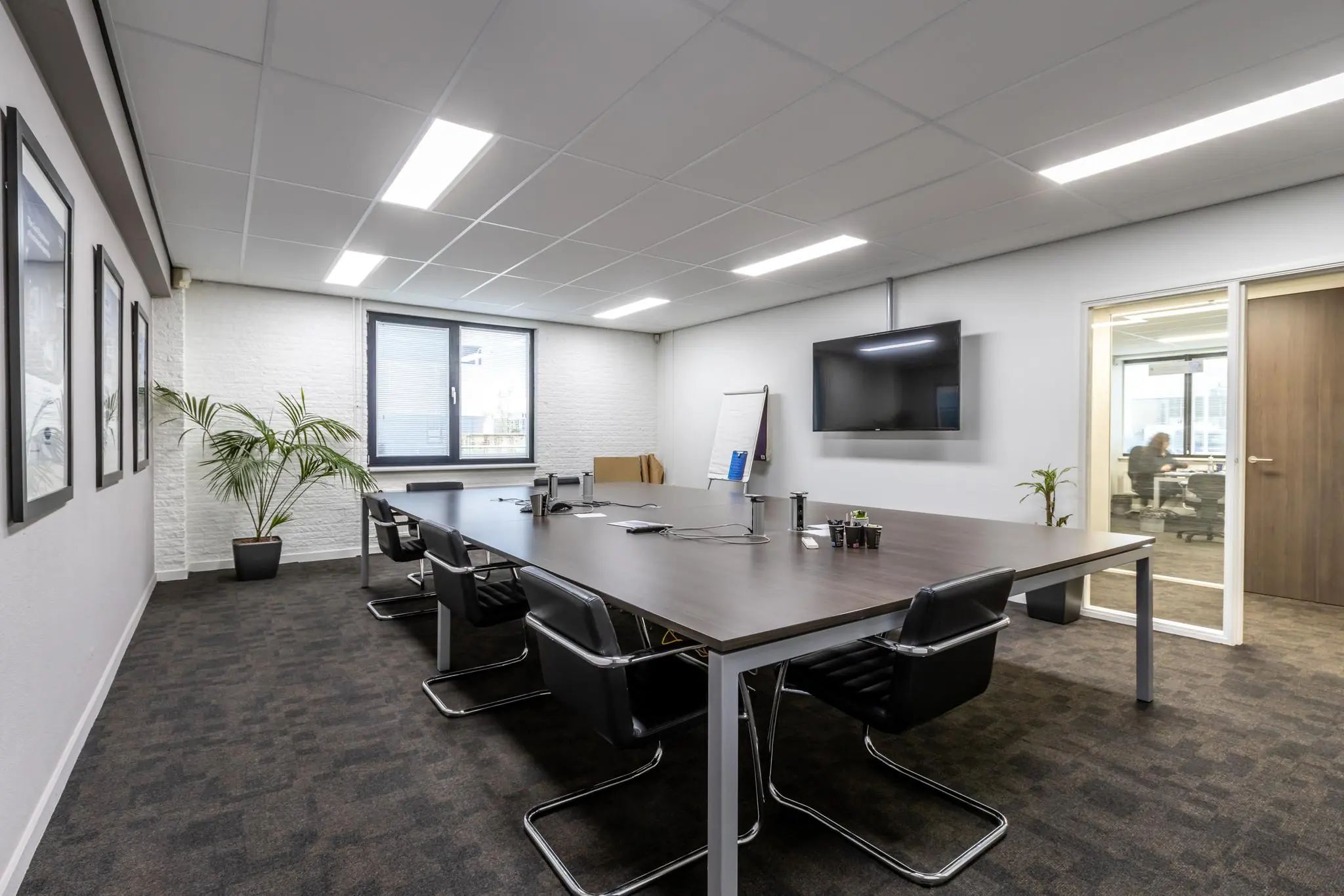 Moderne vergaderruimte aan de Pittsburghstraat met een lange tafel, zwarte stoelen, een flatscreen en grote ramen.