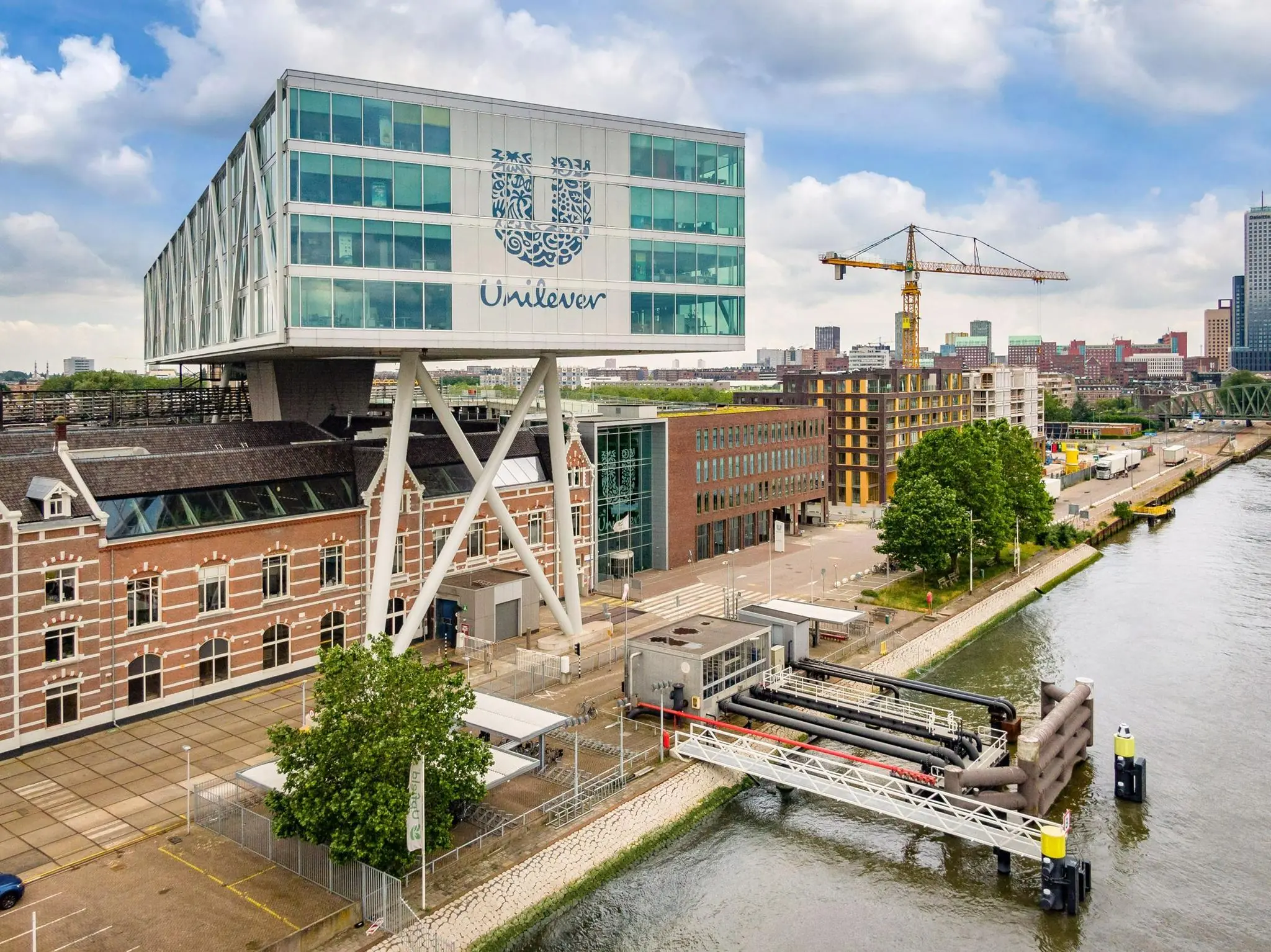 Luchtfoto van het Unilever-gebouw aan de Nassaukade in Rotterdam, gelegen aan de waterkant met een mix van moderne en historische architectuur.
