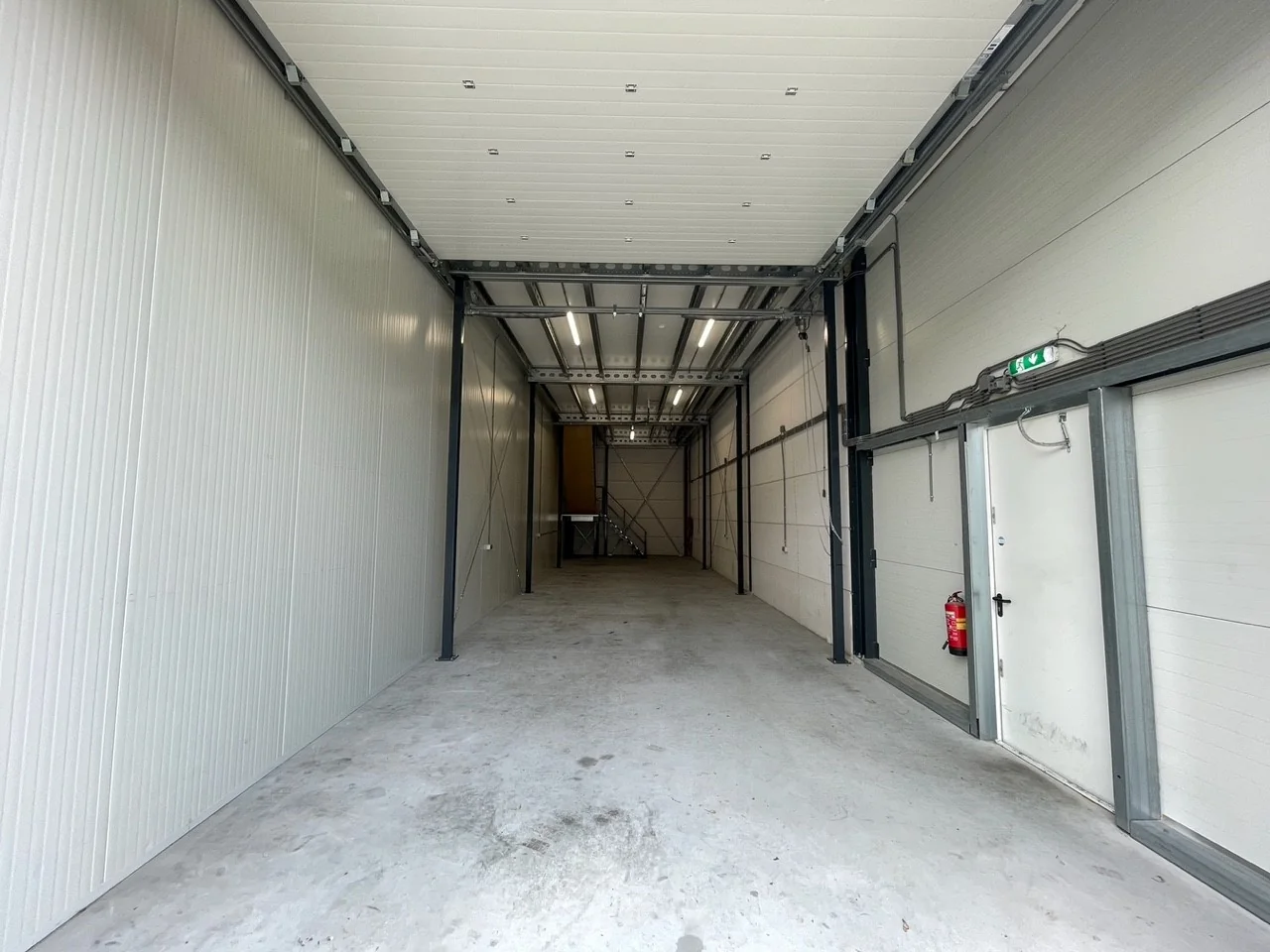 Lege, diepe bedrijfsruimte aan de Aalsmeerderweg met betonnen vloer en witte paneelwanden.