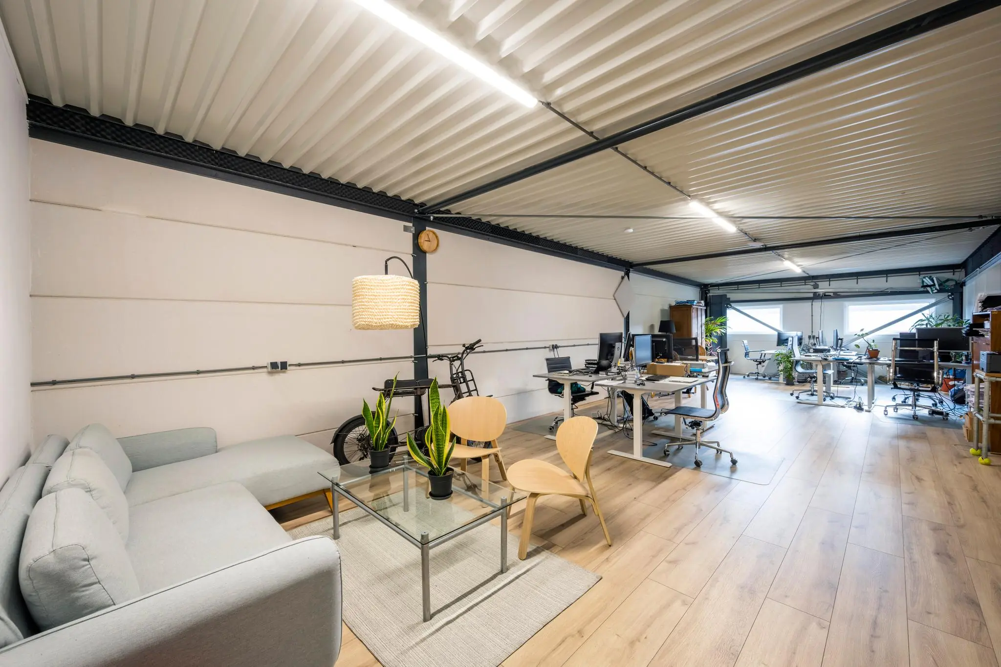 Modern kantoorinterieur aan de Aalsmeerderweg met werkplekken, zithoek en houten vloer.
