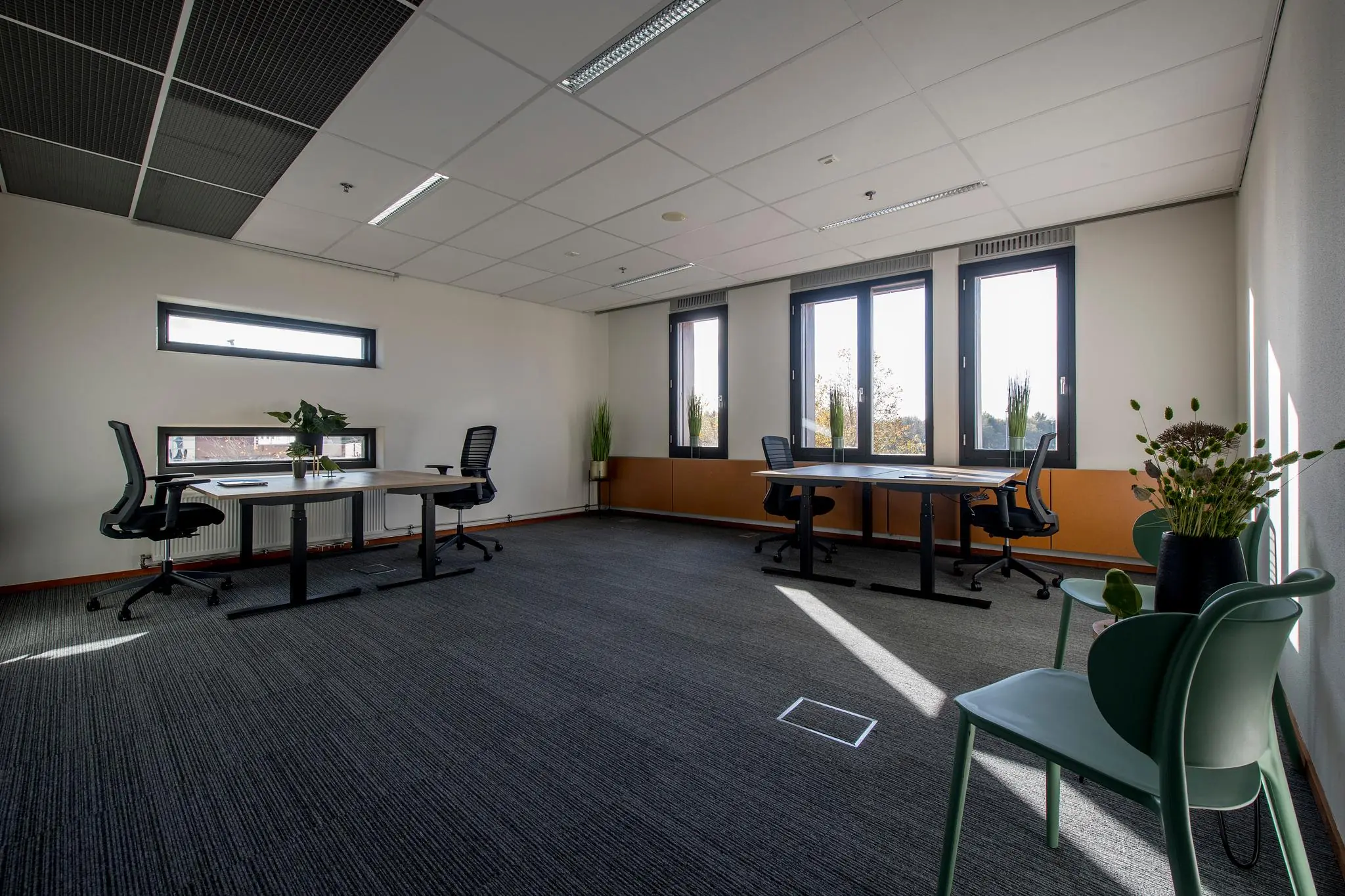 Modern en licht kantoor aan de Fokkerstraat met meerdere werkplekken, bureaustoelen en grote ramen.