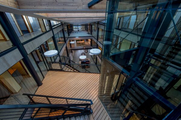 Modern kantoorgebouw aan de Fokkerstraat met glazen wanden, houten vloeren en meerdere verdiepingen rondom een open atrium.
