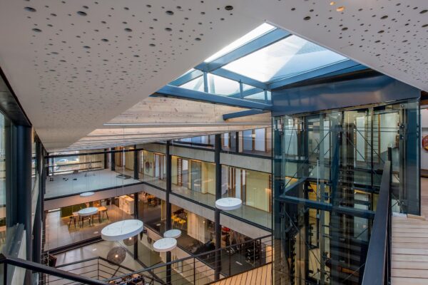 Modern kantoorgebouw aan de Fokkerstraat met open atrium, glazen lift en designverlichting.