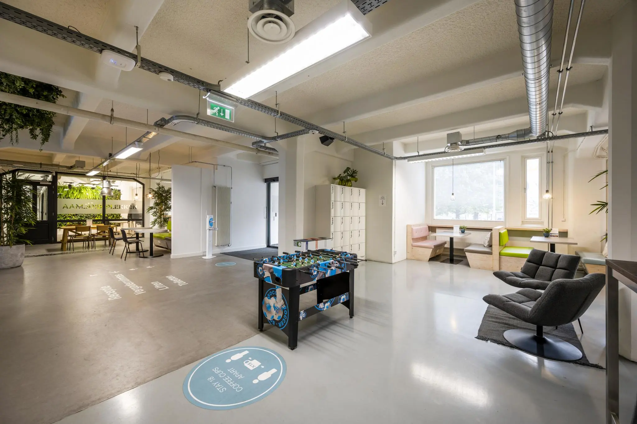 Moderne en open kantoorruimte aan de Van Diemenstraat met zitjes, lockers, een tafelvoetbaltafel en veel groen.