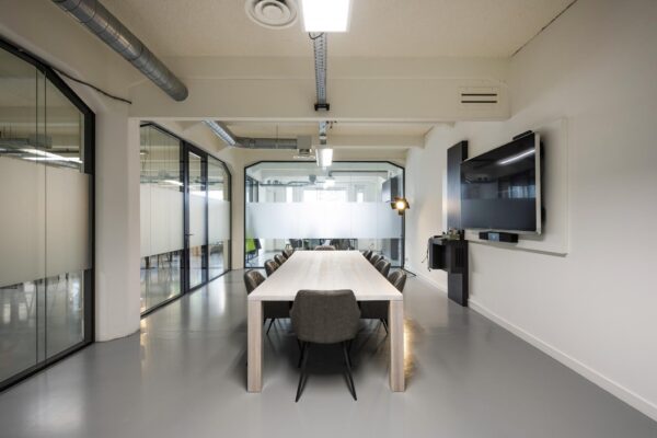Moderne vergaderruimte aan de Van Diemenstraat met een lange tafel, glazen wanden en een groot presentatiescherm.