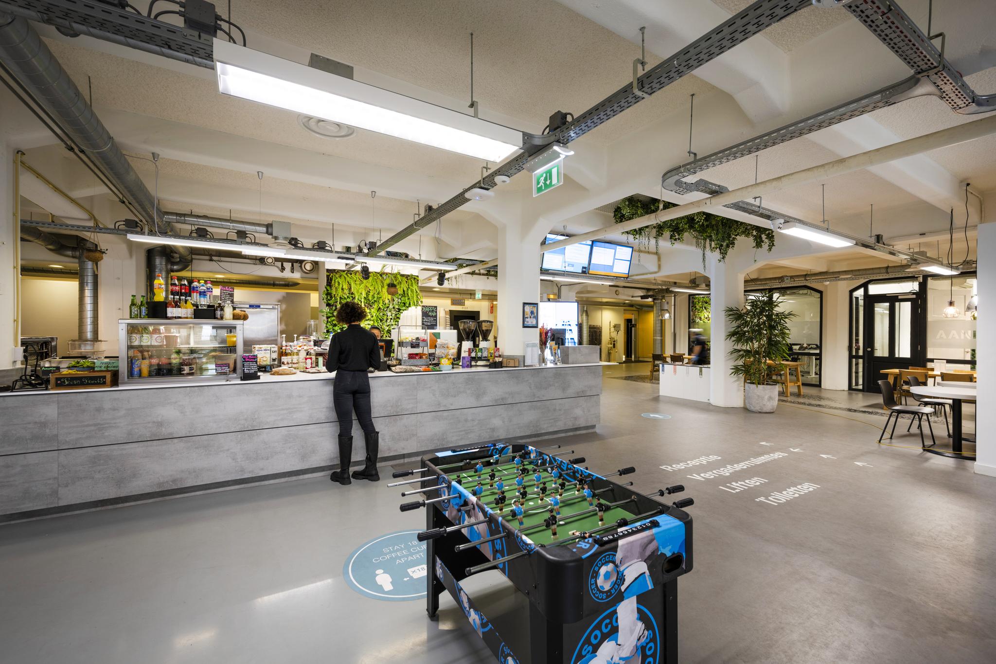 Moderne, open kantoorcafetaria aan de Van Diemenstraat met een voetbaltafel en groene accenten.
