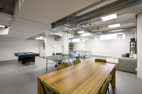 Moderne ontspanningsruimte aan de Van Diemenstraat met een biljarttafel, tafeltennistafel, zitgedeelte en grote houten vergadertafel.