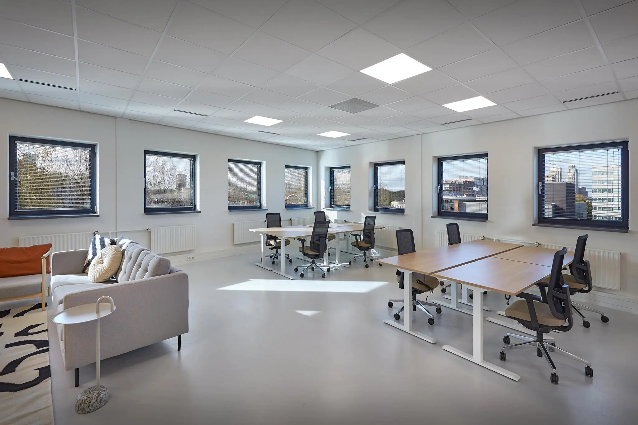 Licht en modern kantoor met werkplekken en een zithoek aan de Joop Geesinkweg in Amsterdam.
