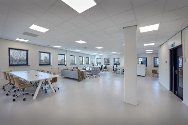 Moderne, open kantoorruimte aan de Joop Geesinkweg met vergadertafels, werkplekken en zithoek.