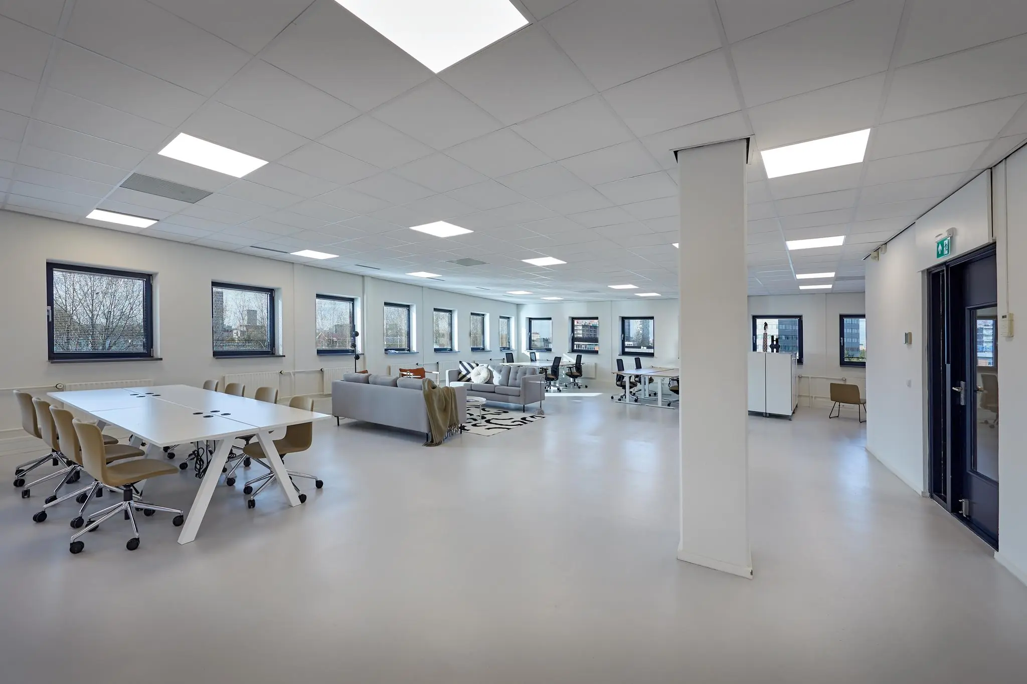 Moderne, open kantoorruimte aan de Joop Geesinkweg met vergadertafels, werkplekken en zithoek.