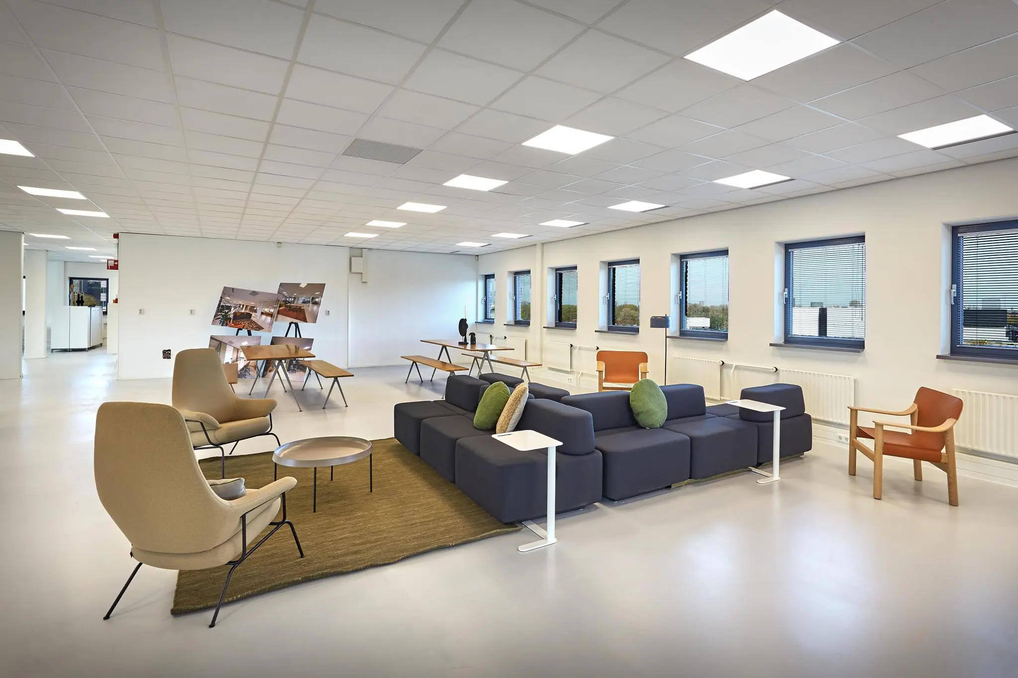 Moderne en ruime lounge- en werkruimte aan de Joop Geesinkweg met zitplekken, tafels en grote ramen.