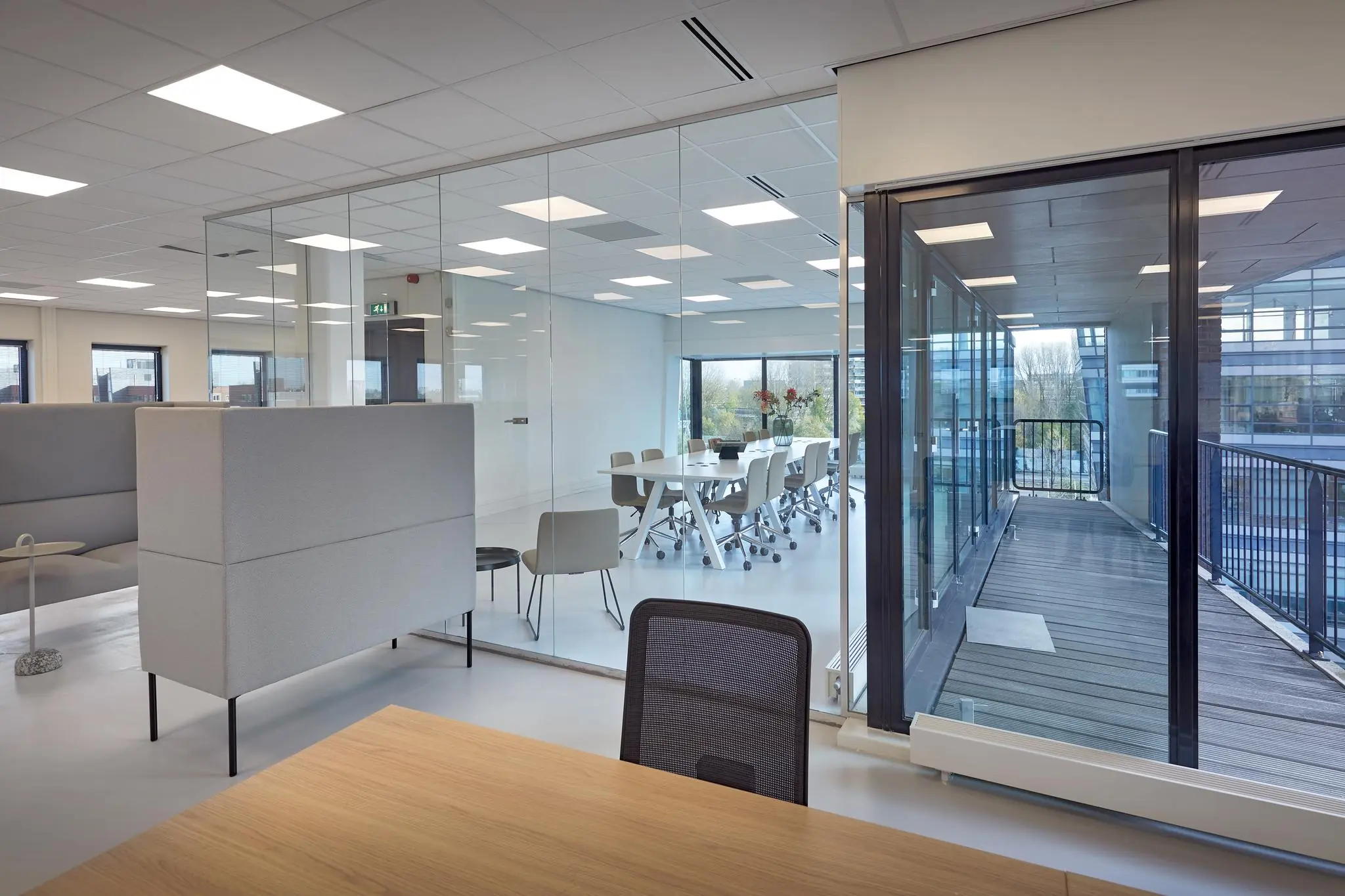 Moderne kantoorruimte aan de Joop Geesinkweg met glazen vergaderruimte en uitzicht op een balkon.