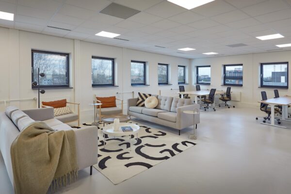 Moderne, lichte kantoorruimte aan de Joop Geesinkweg met een zithoek, bureaus en grote ramen.