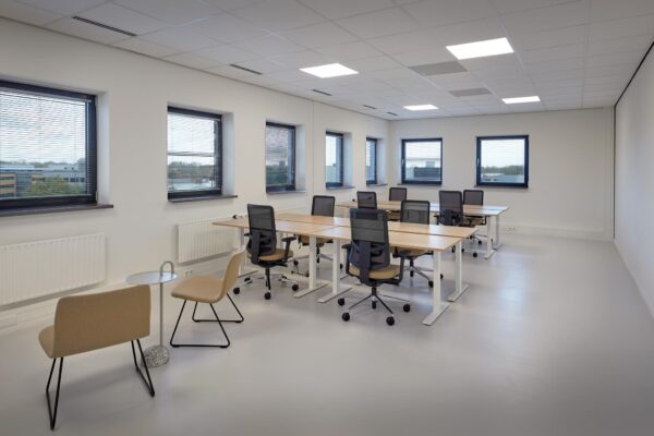 Moderne kantoorruimte aan de Joop Geesinkweg met bureaus, bureaustoelen en grote ramen met zonwering.