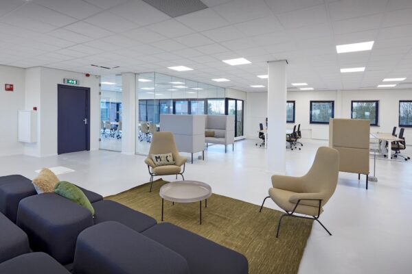 Moderne, open kantoorruimte aan de Joop Geesinkweg met loungegedeelte, werkplekken en glazen vergaderruimte.