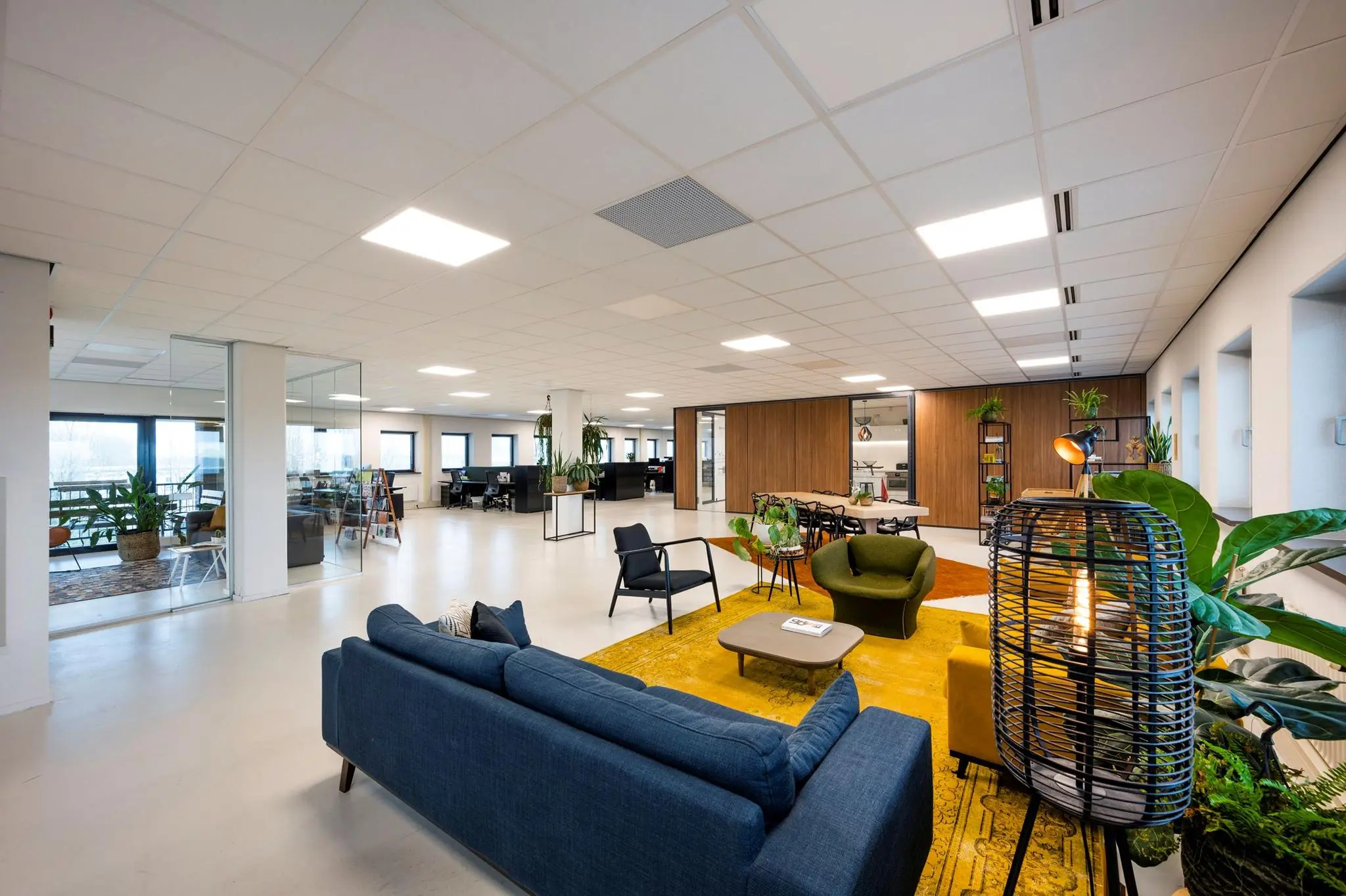Moderne en ruimtelijke kantoorruimte aan de Joop Geesinkweg met een open indeling, loungehoek, vergaderruimte en veel planten.
